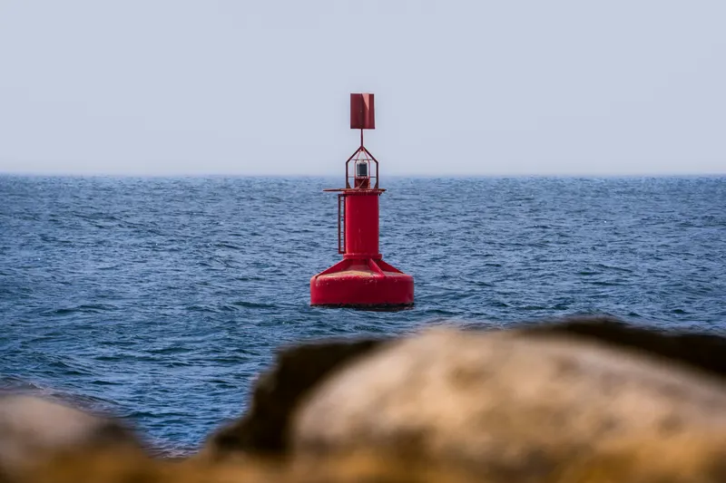 Boya lateral roja con marca de tope cilíndrica en mar abierto.